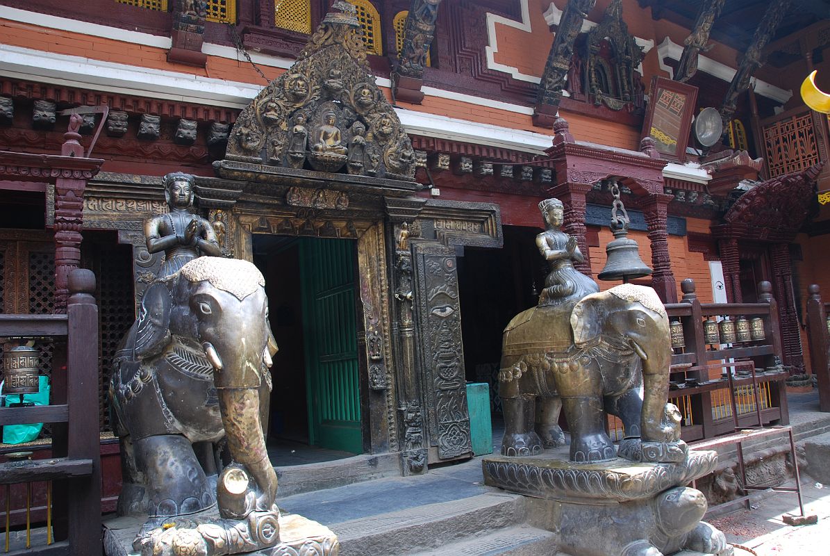 Kathmandu Patan Golden Temple 06 Elephants Guard Entrance From Inside Courtyard On either side of the entrance in the courtyard of the Golden Temple in Patan are two metal statues of elephants standing on tortoises. Between the elephants is the exquisite carved doorway with Buddha and the five Dhyani Buddhas on the arch above the entrance.